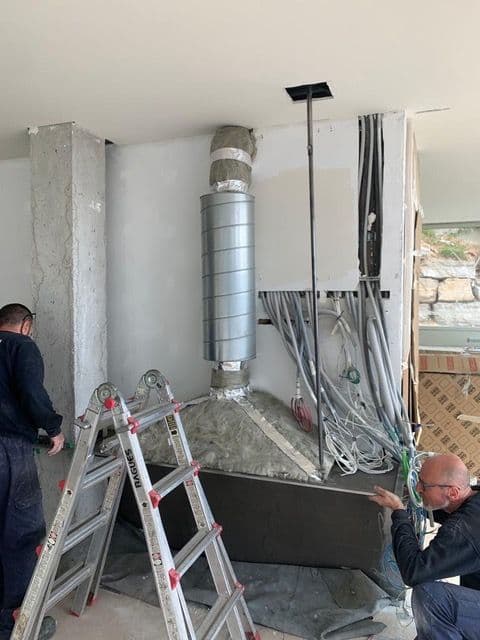 Dos hombres están trabajando en una habitación con una escalera.