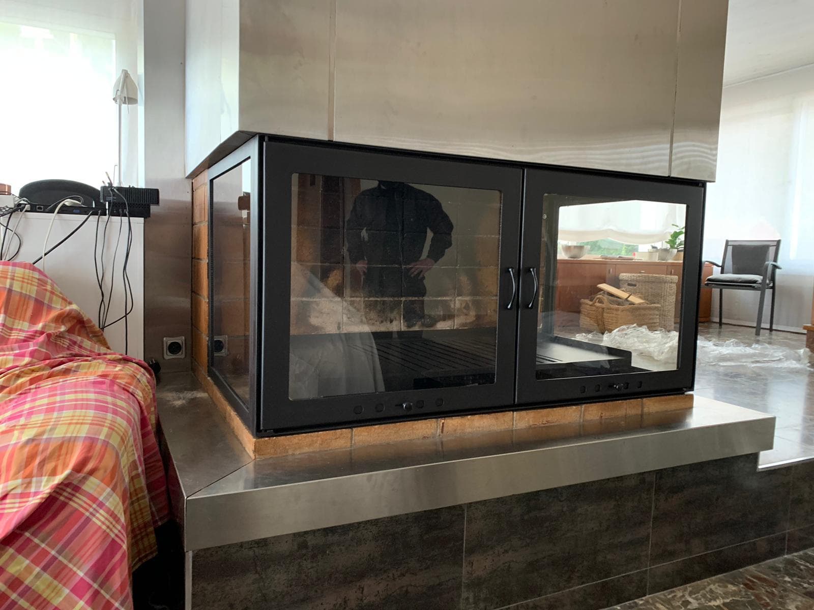 Chimenea de leña con cerramiento acristalado hecho a medida en el centro de un salón