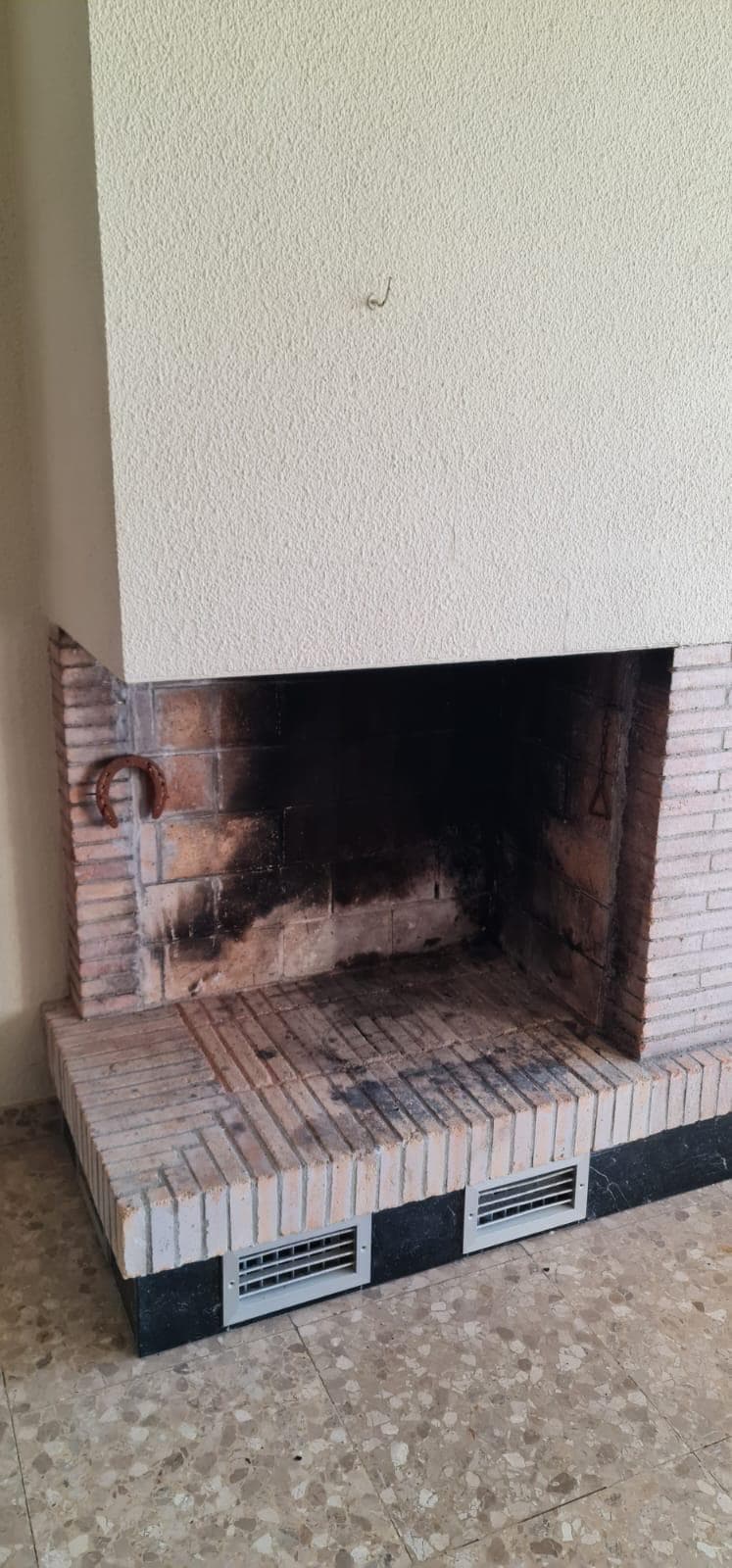 Chimenea de leña abierta de ladrillo, ennegrecida por el uso, antes del cerramiento
