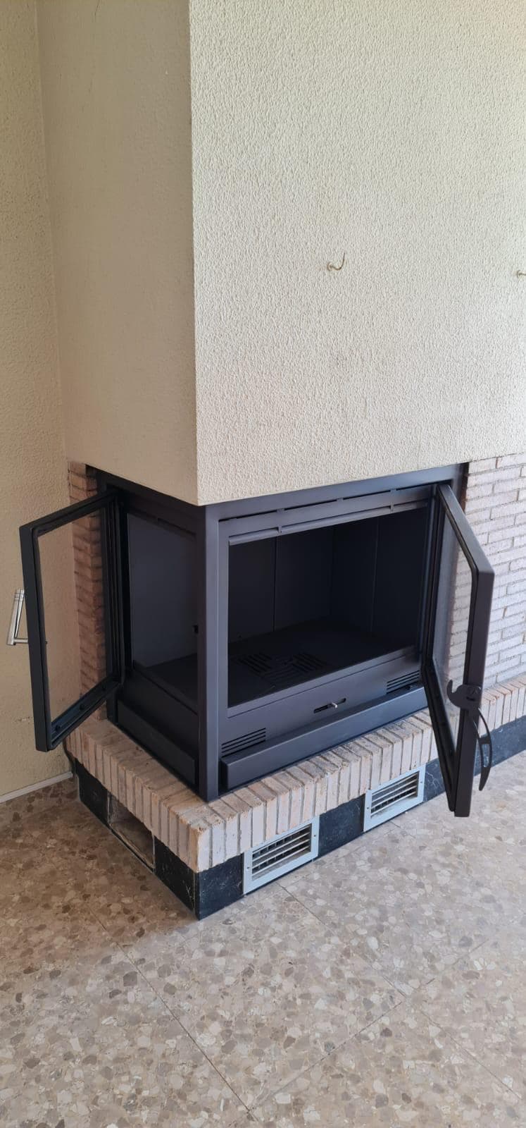 Chimenea de leña cerrada con un cerramiento a medida con puerta de cristal y regulador de tiro