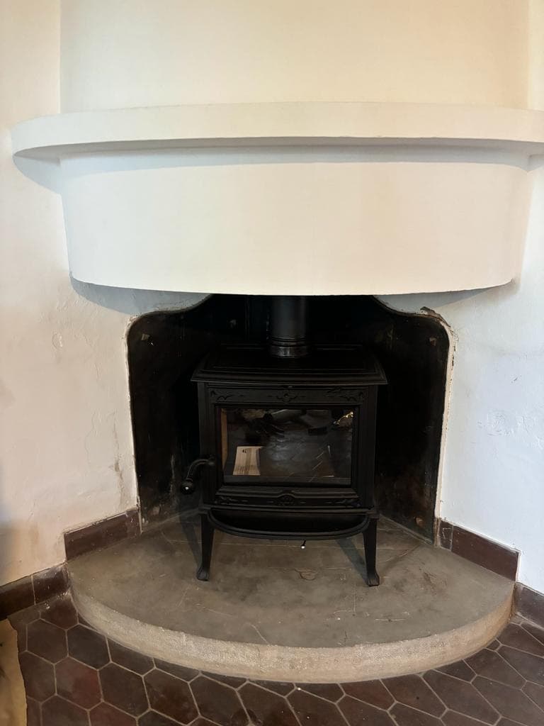 Estufa de leña colocada dentro de una chimenea de obra antigua