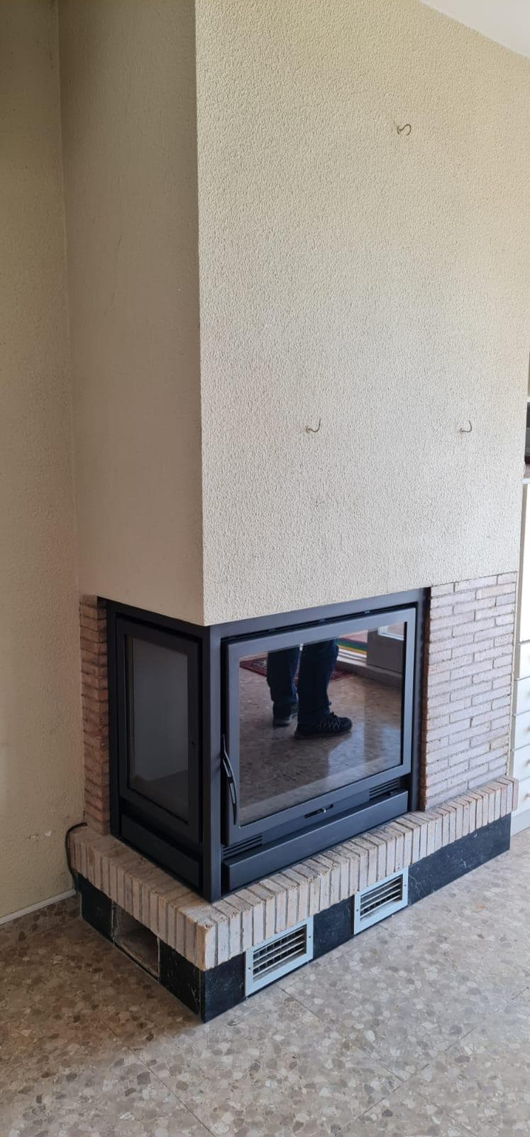 La misma chimenea de esquina cerrada con un cassette de leña con cristal en el frente y en el lateral