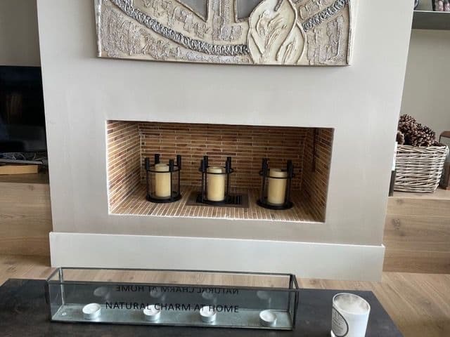 Disused masonry wood fireplace, with the brick firebox decorated with candles, before the refurbishment
