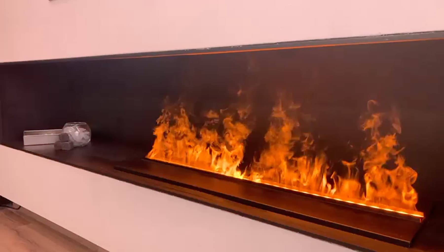 Xemeneia elèctrica de vapor d'aigua encesa, vista de biaix, encastada en un frontal negre