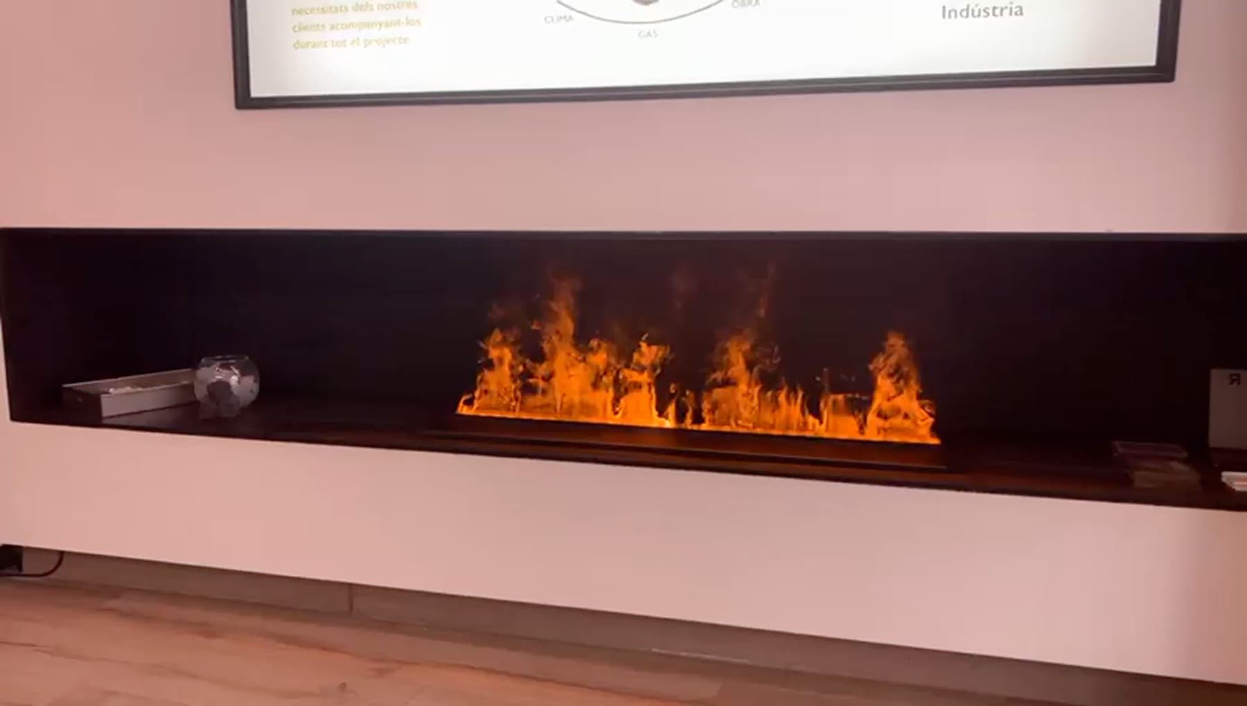 Xemeneia elèctrica decorativa de vapor d'aigua, lineal, encastada en un frontal negre en una paret blanca