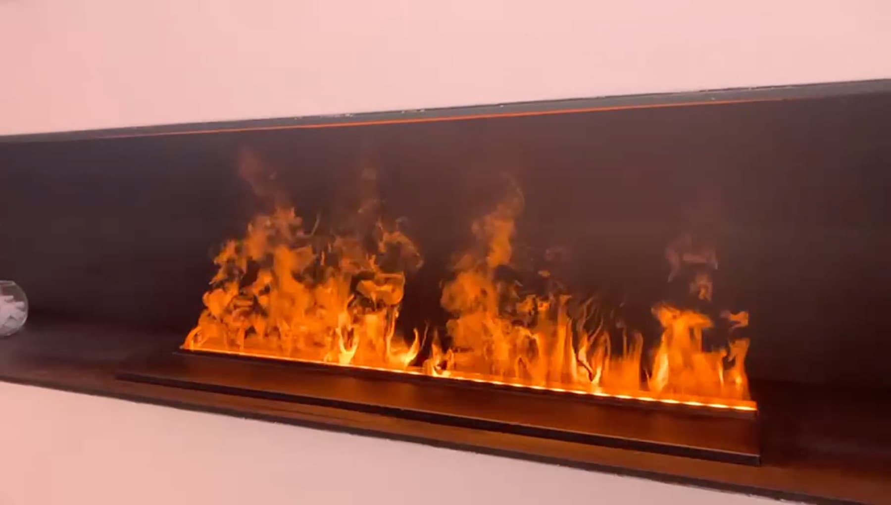 Flames de vapor d'aigua il·luminades en una xemeneia elèctrica lineal encastada en un frontal negre