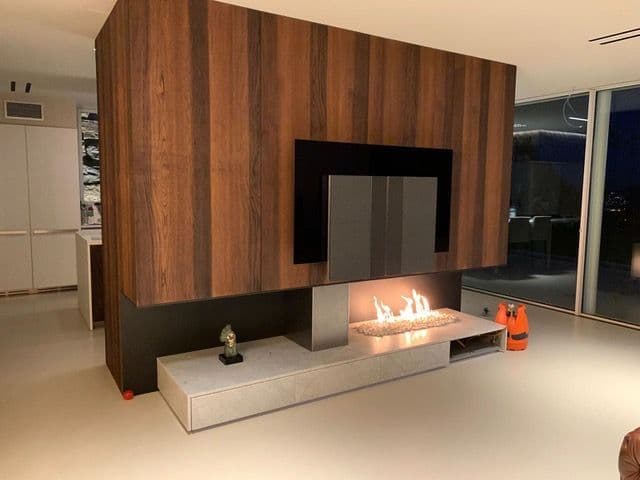 Finished gas fireplace under the television, with wooden cladding