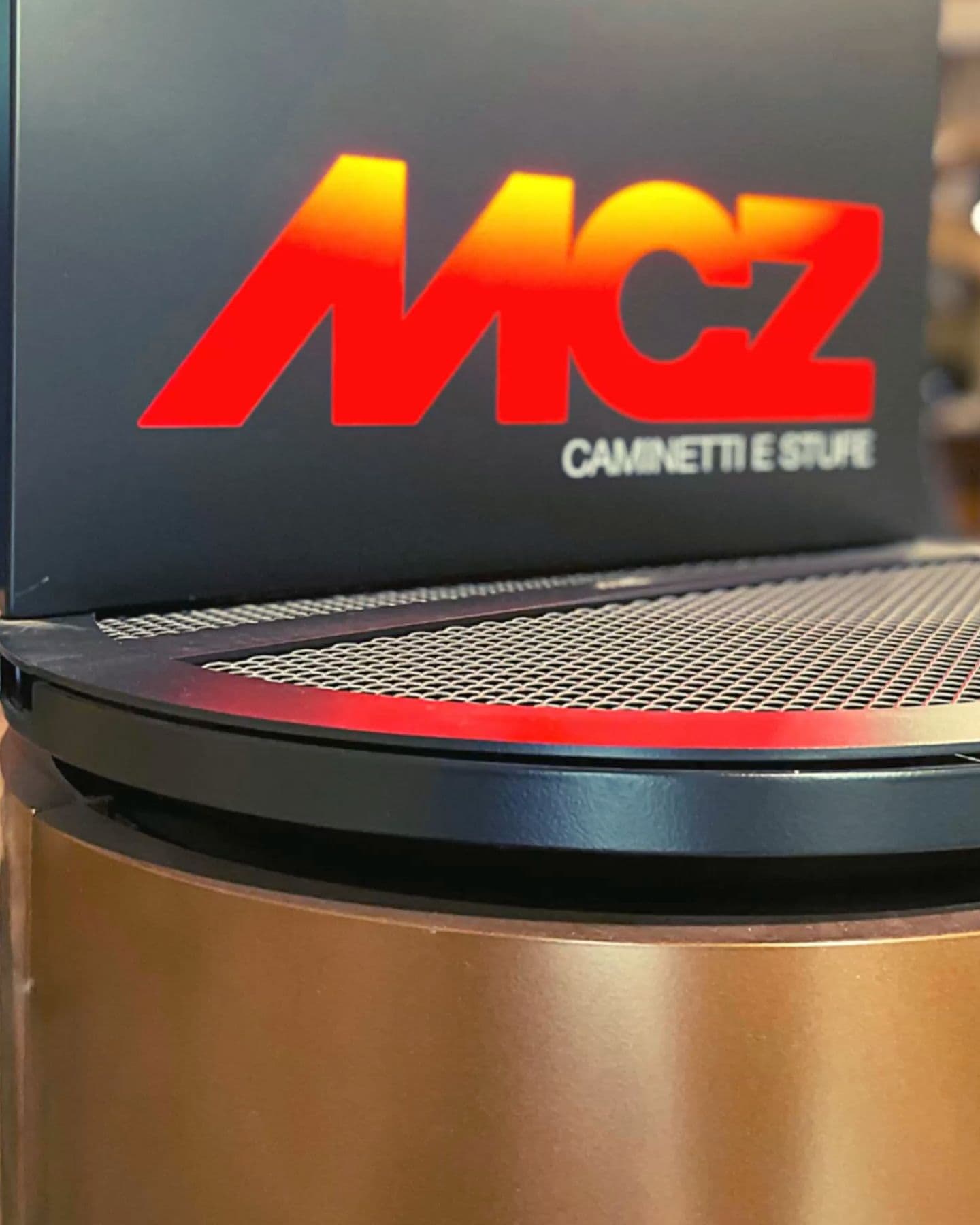 Estufa de pellet MCZ de cuerpo color cobre con el rótulo de la marca, en nuestro showroom de Barcelona