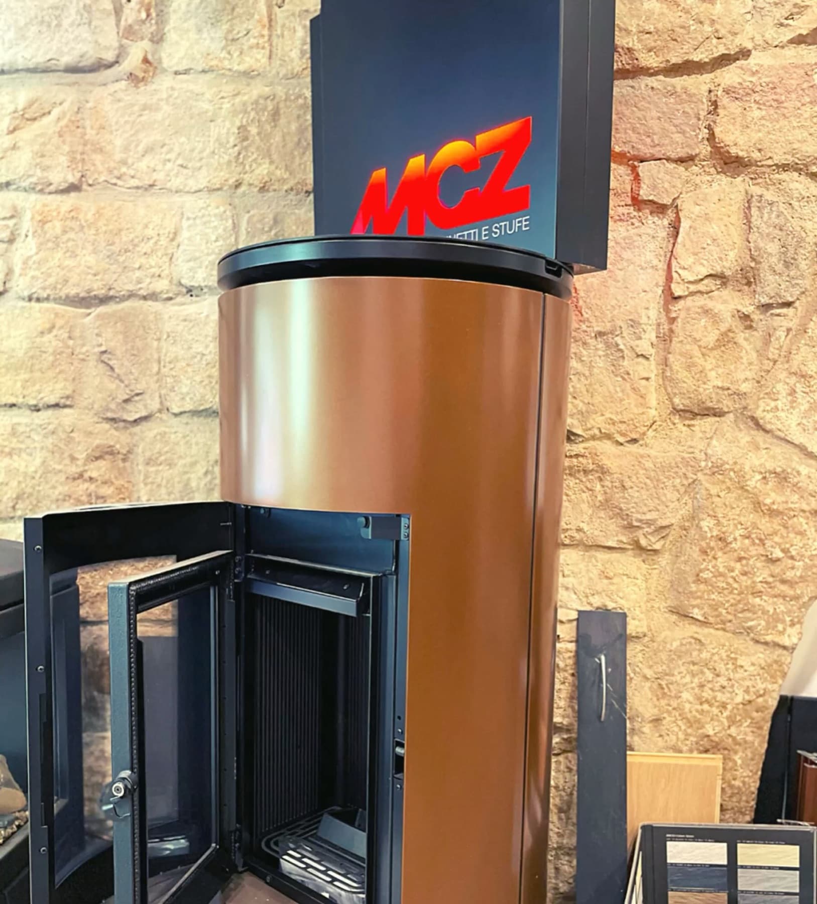 Estufa de pellet MCZ de cuerpo cilíndrico con la puerta abierta, en nuestro showroom de Barcelona