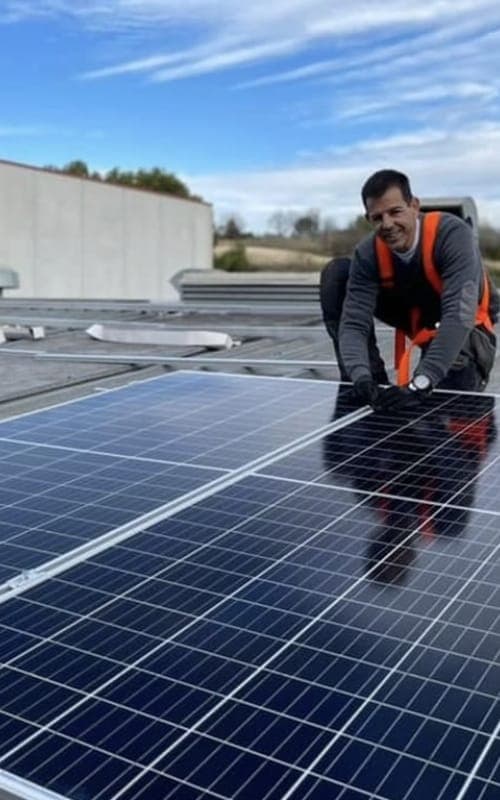 Tècnic amb arnès de seguretat col·locant un panell solar fotovoltaic en una coberta