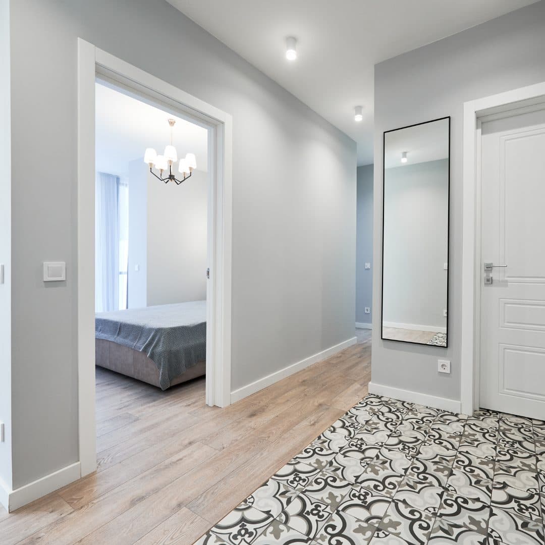 Refurbished hallway with a wooden floor and patterned encaustic tiles, with no radiators in sight