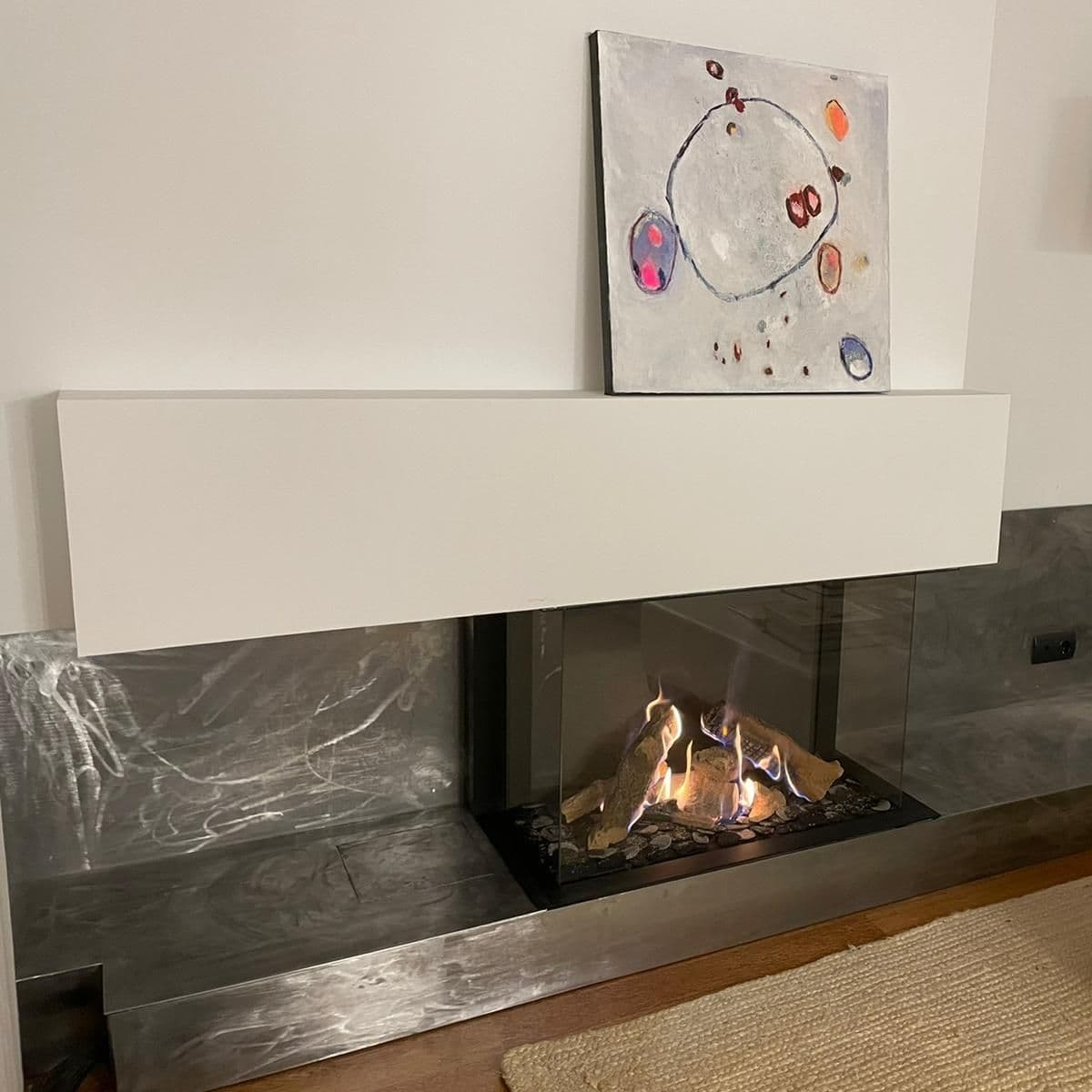 Mantenimiento de chimeneas: chimenea de gas estanca encendida con troncos cerámicos, en una pared revestida de metal