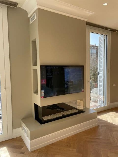 Chimenea de gas estanca con salida de gases forzada bajo el televisor de un salón en Igualada