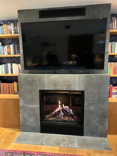 Front-view room-sealed gas fireplace with the television above, ready for its service