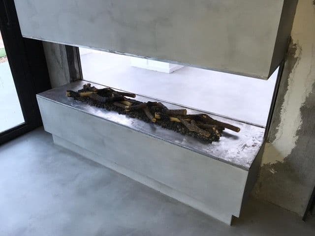 See-through gas fireplace during the work, with ceramic logs on the burner