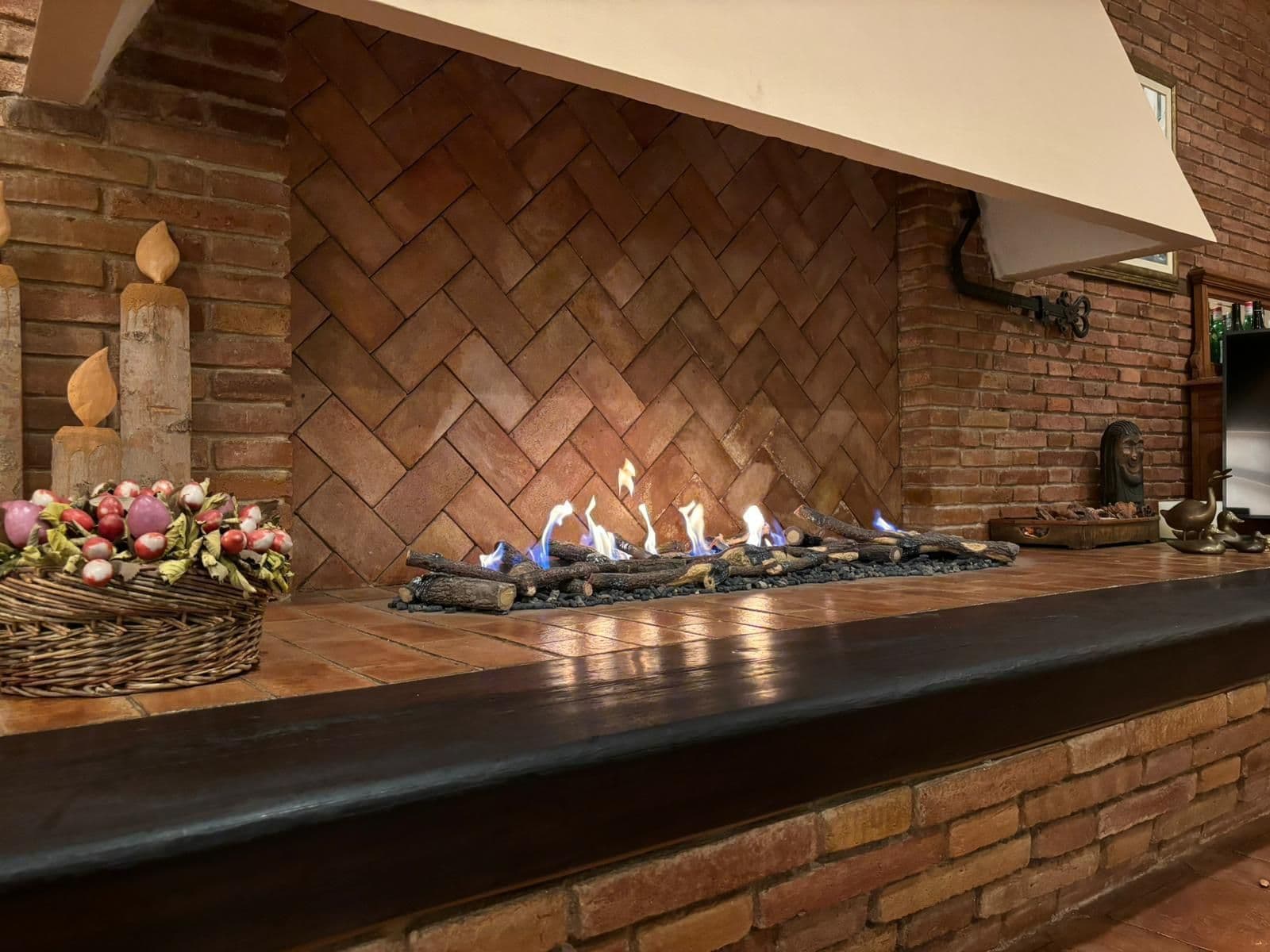 Chimenea de gas atmosférica encendida sobre troncos cerámicos en un antiguo hogar de ladrillo