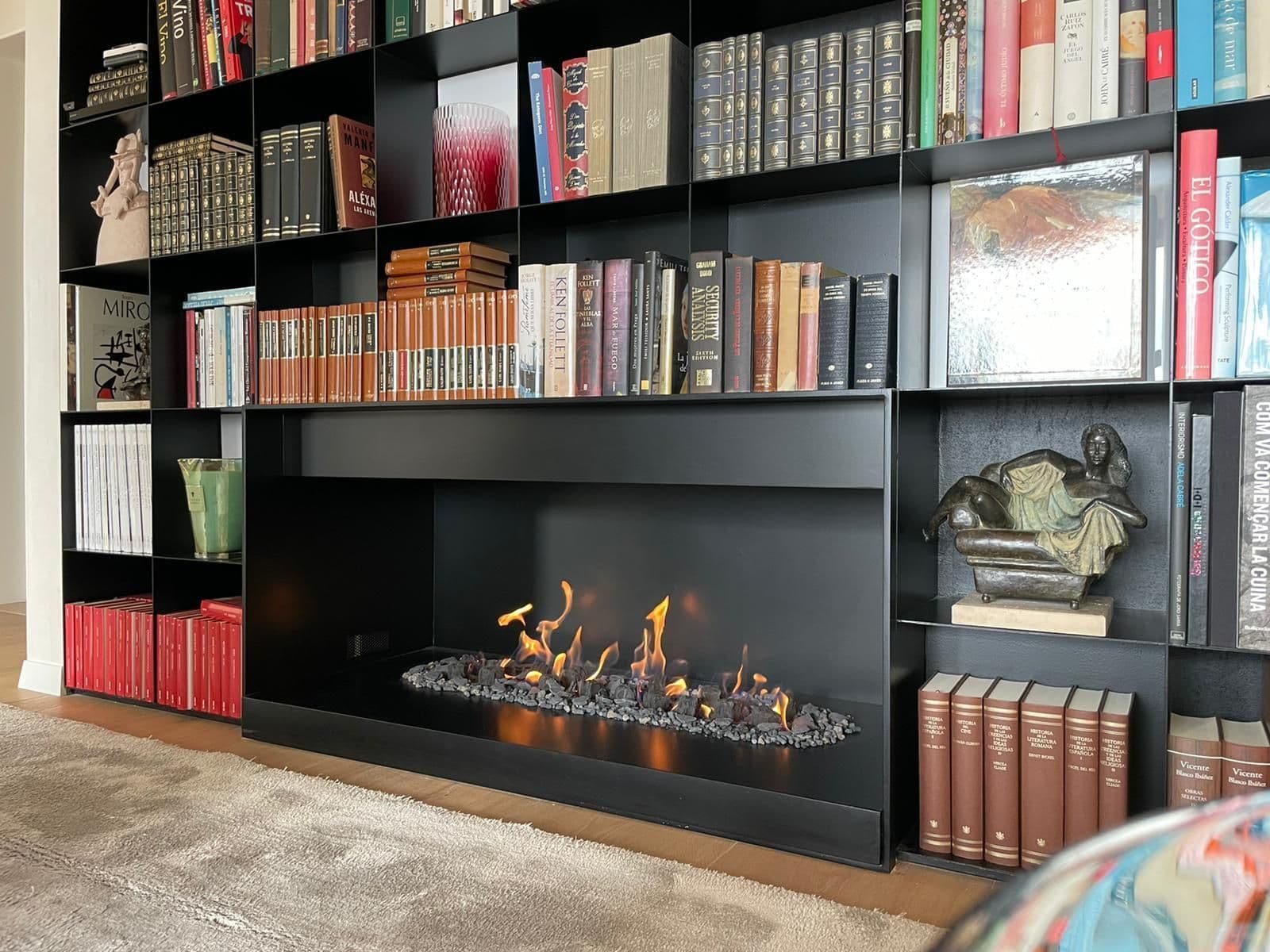 Chimenea de gas atmosférica integrada en una librería de hierro negro hecha a medida en Barcelona