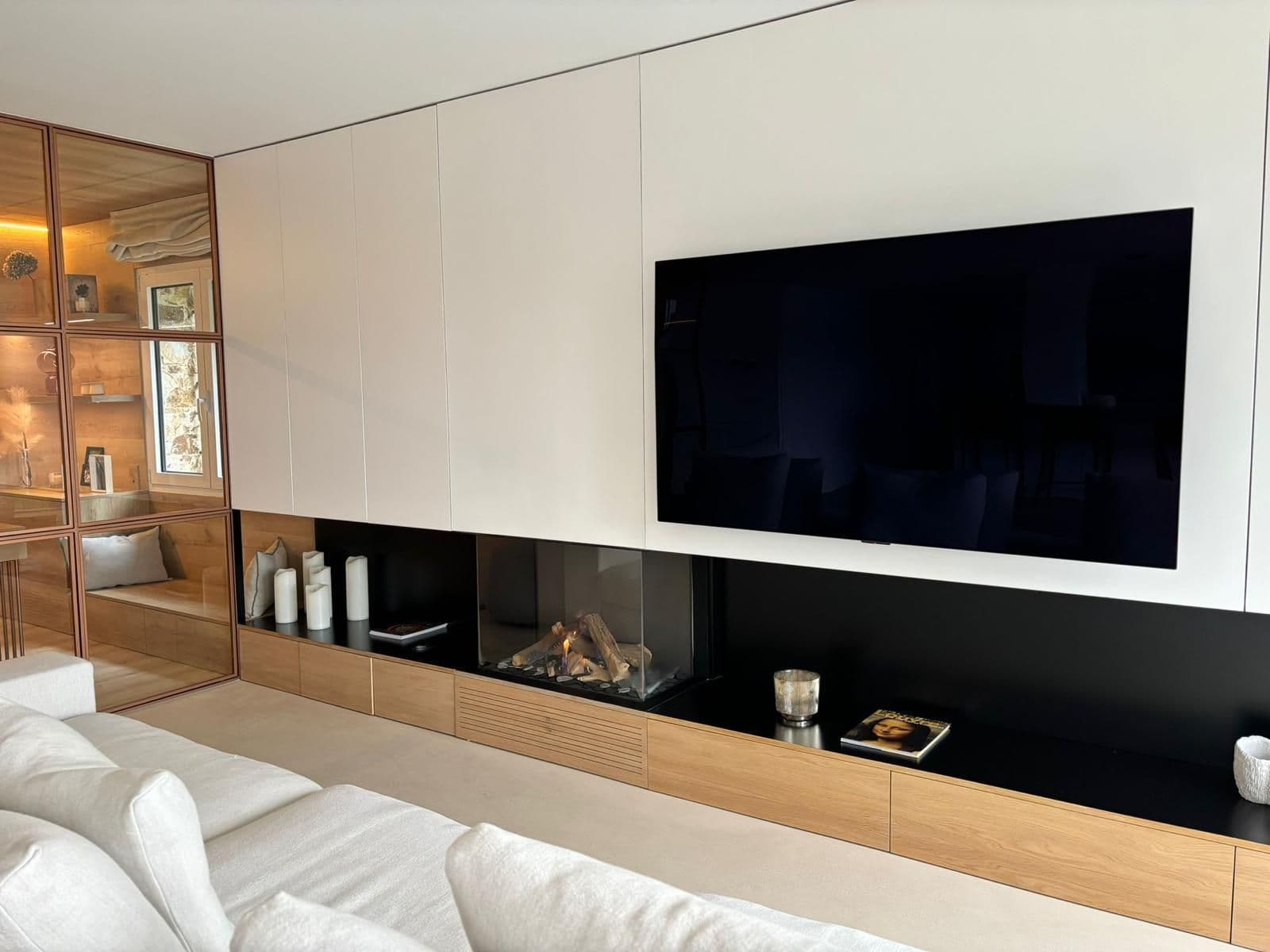 Chimenea de gas estanca lineal integrada en un mueble blanco bajo el televisor, junto a una vitrina