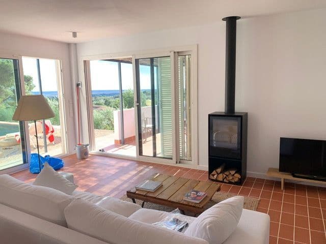 Estufa de leña exenta con el tubo a la vista en un salón con suelo de barro, en Perelló