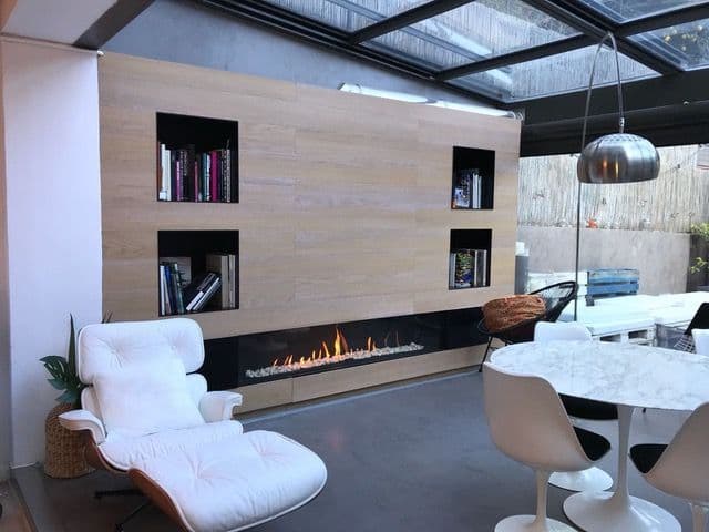 Chimenea de gas estanca de tres caras con nichos de hierro y aplacado de madera natural en Barcelona